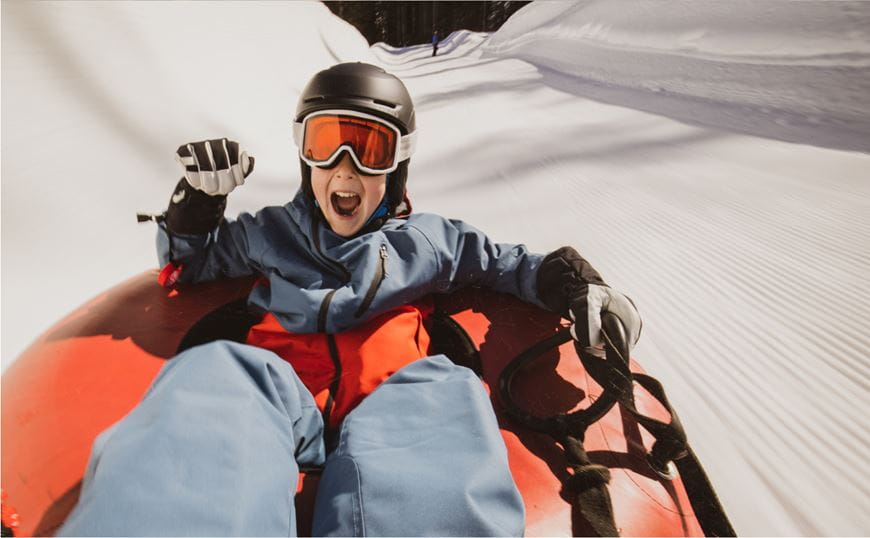 Child smiling on a snow tube on a hill