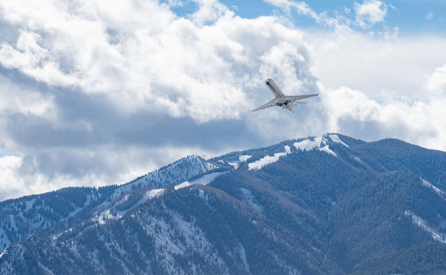 Plane taking off from Aspen-Pitkin County Airport with Aspen Highlands in the background