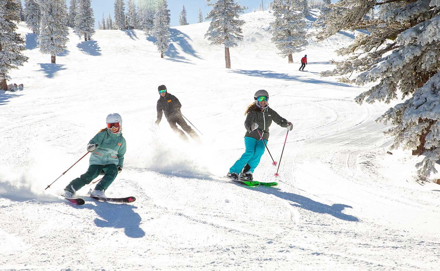 A family of three descends a fun ski run at Snowmass