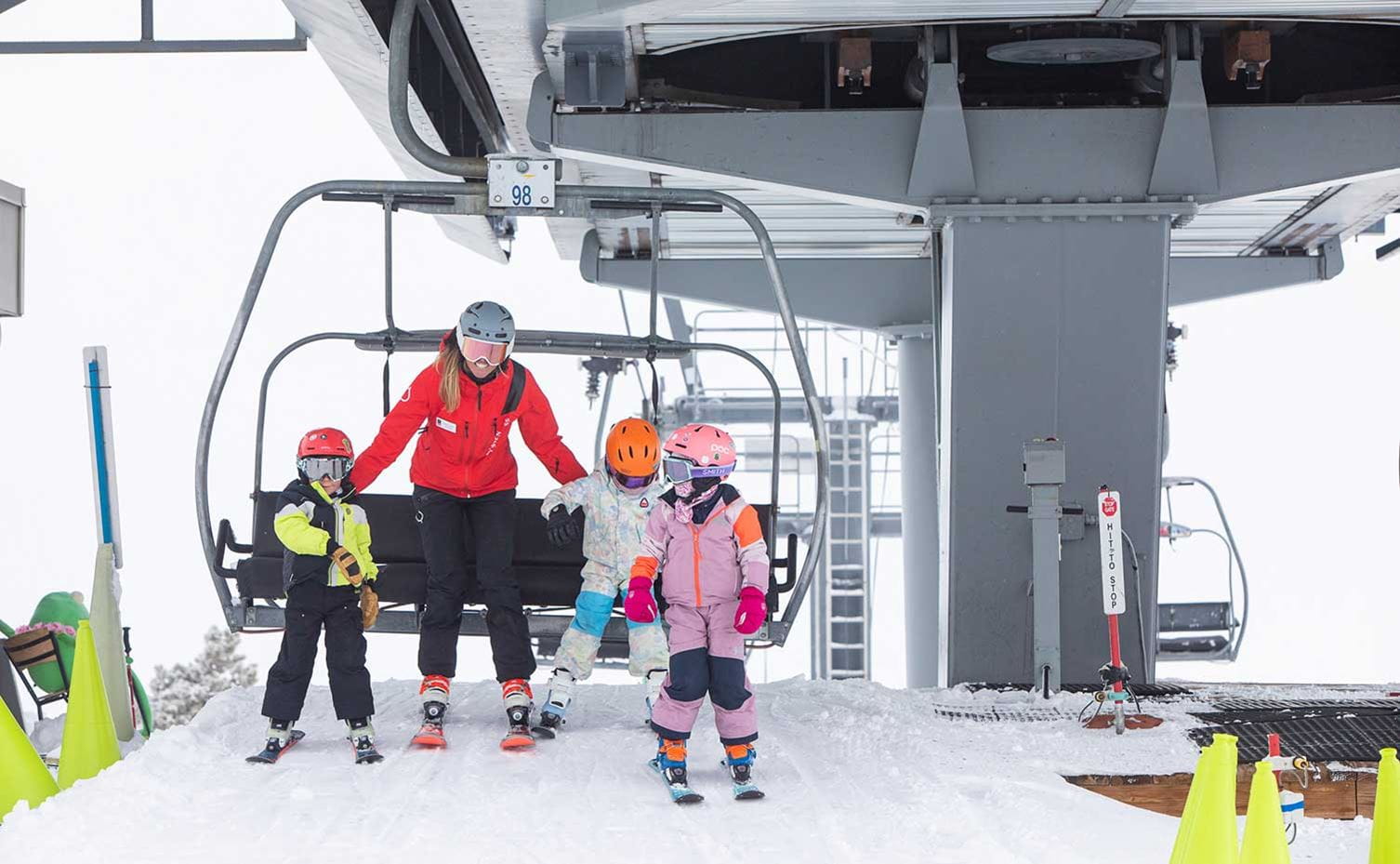 A ski school instructor at Buttermilk helps two kids get off the lift.