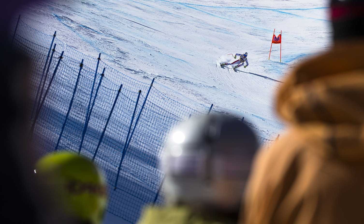 A ski racer descends Aspen Mountain while spectators watch