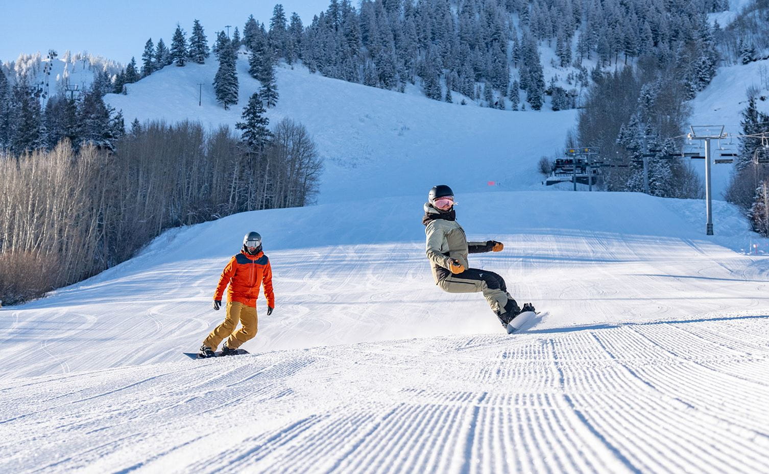 A skier and a snowboarder ride down a groomer at Aspen Mountain