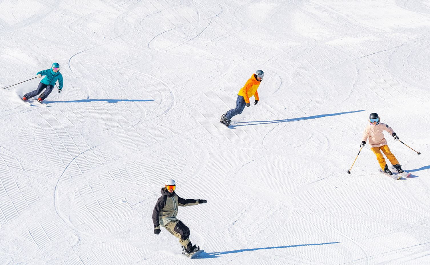 Three skiers and a snowboarder descend the slopes at Aspen Snowmass