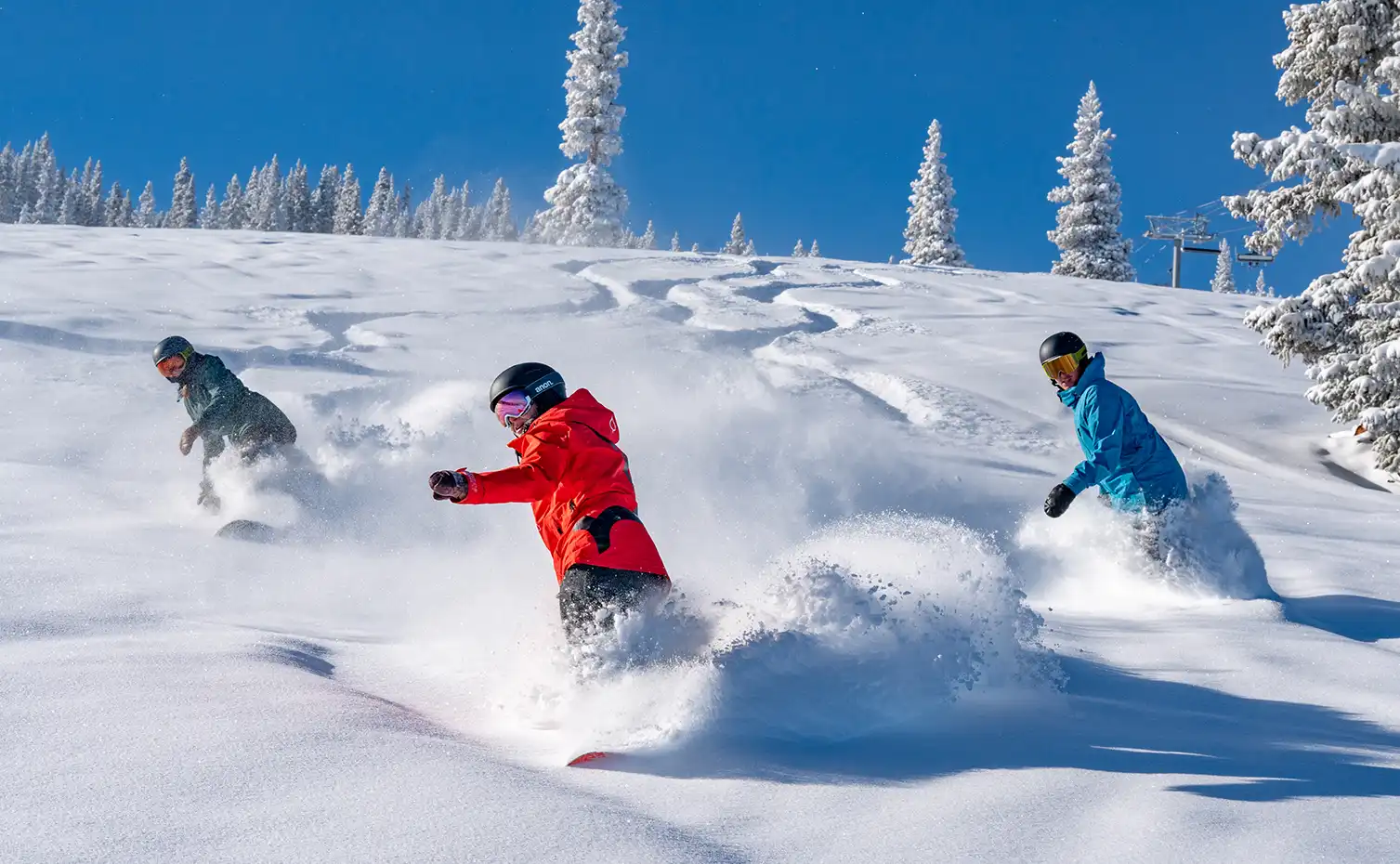 Three people enjoying great powder during a Locals Clinic