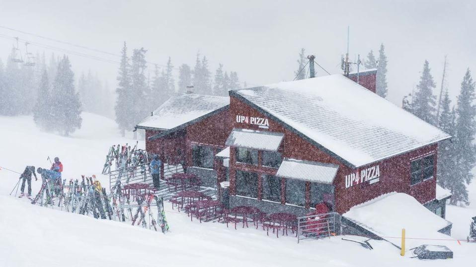 Exterior view of Up4Pizza building, small red cabin on the top of Snowmass, snow falls peacefully around it