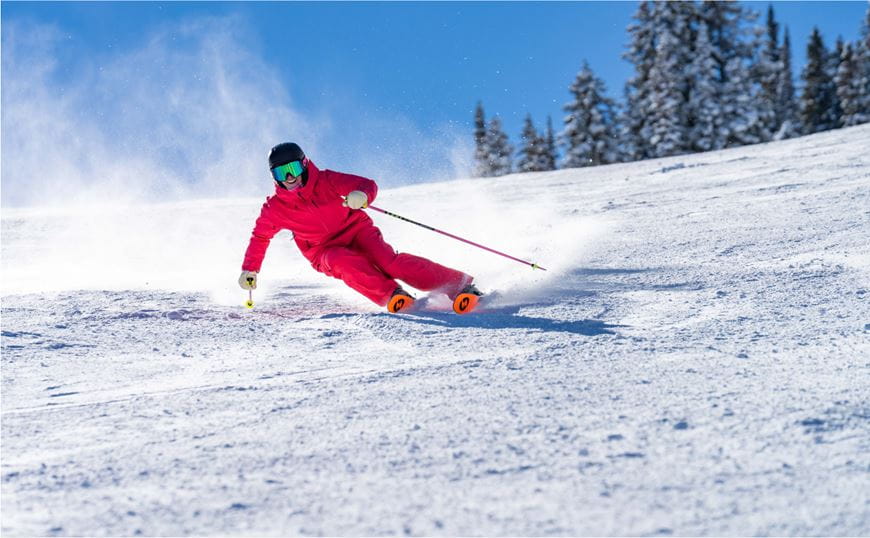 Person in red ski outfit carving on a ski slope 