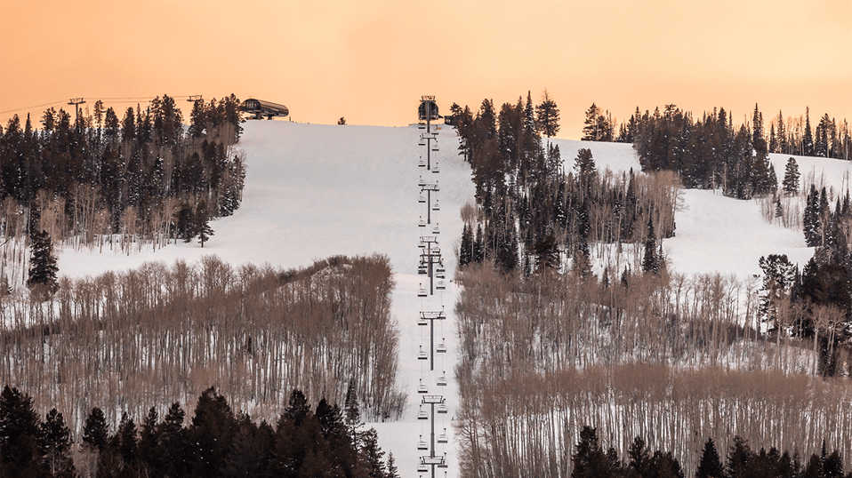 Buttermilk Mountain at dusk, orange sky over white slopes and winter coated trees