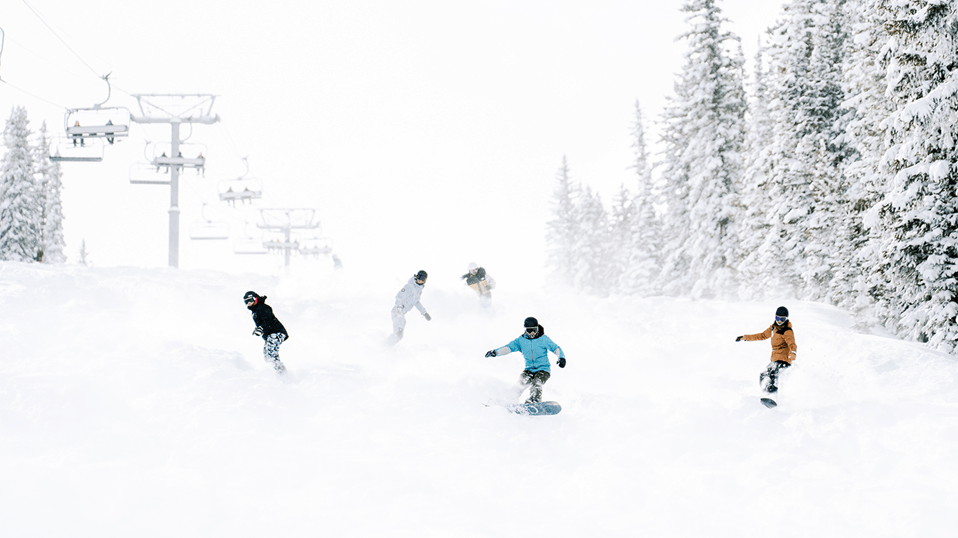 Snowboarders and skiers ride down the big burn at Aspen Snowmass in the powder