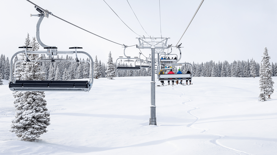 Sitting on the Big Burn lift at Aspen Snowmass, on a sunny powder day. A few deep turns can be seen in the powder below 