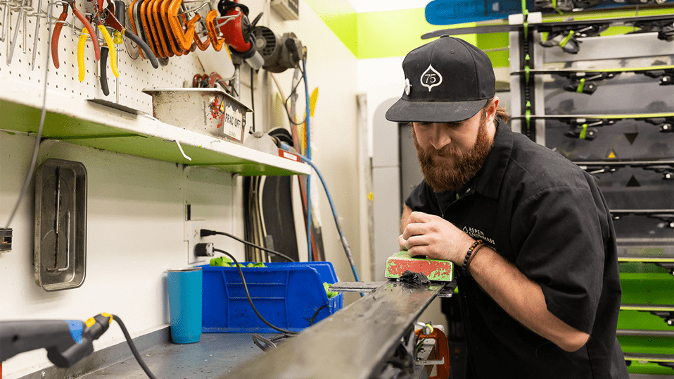 Aspen Highlands Employee works at the Tuning shop, waxing a pair of skies 