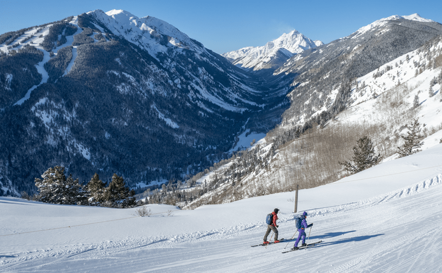 Two people uphill skiing on Buttermilk mountain on a groomed trail