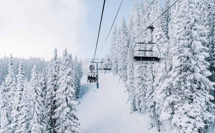 chair lifts travel through snow coated trees at aspen snowmass