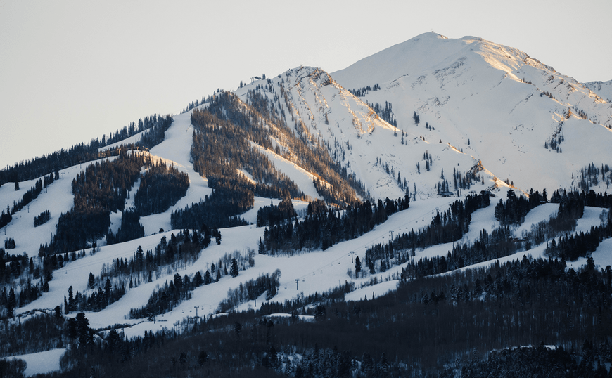 Sun casts a golden glow on the snowy ski runs of aspen highlands