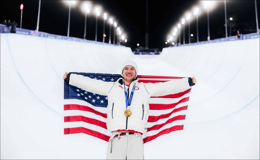 Alex Ferreira holding up USA Flag wearing his gold medal