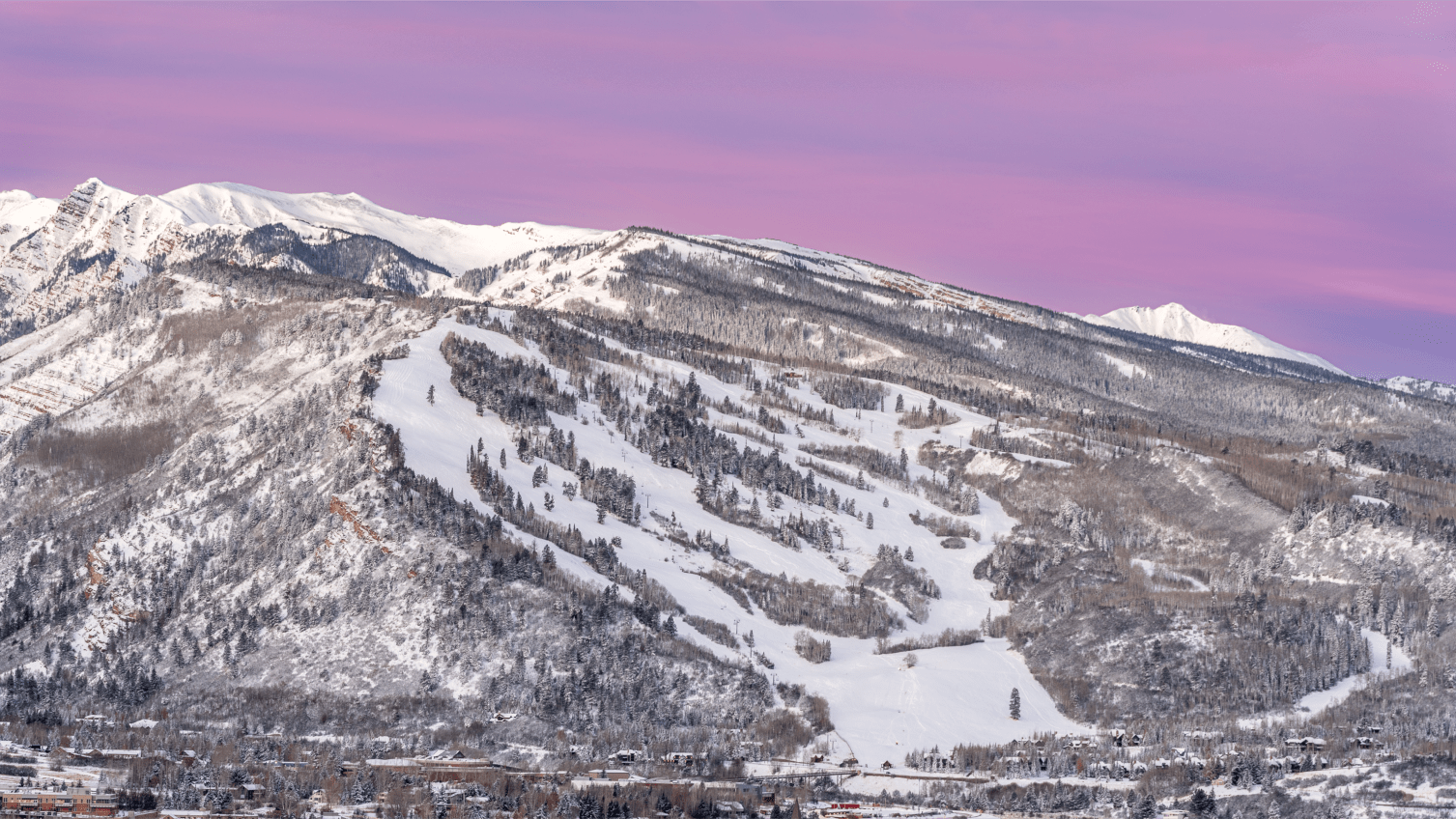 purple skies over the buttermilk ski resorts, white slopes lined by snow capped pine trees