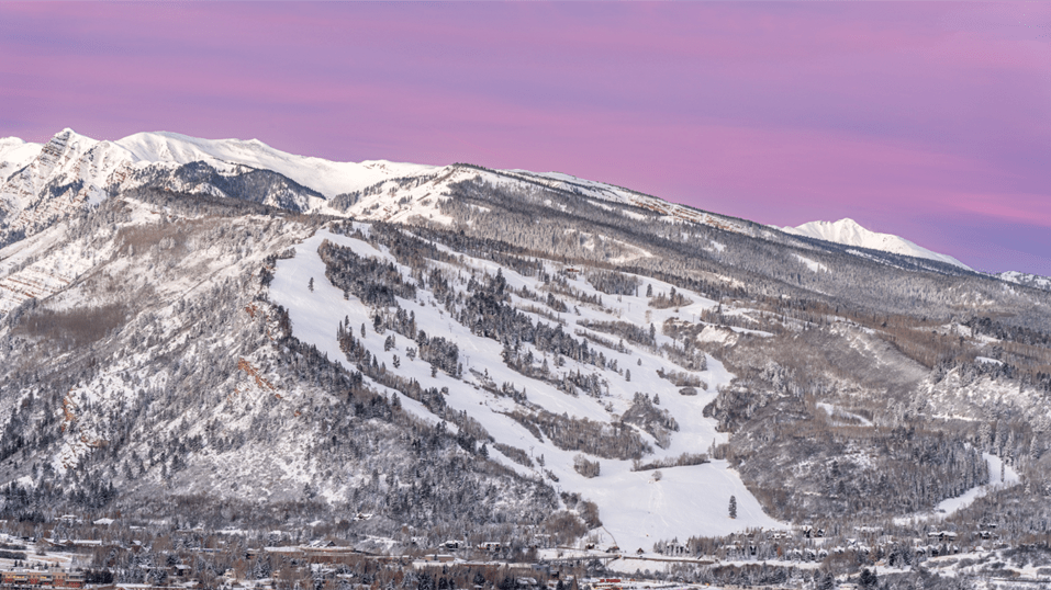 purple skies over the buttermilk ski resorts, white slopes lined by snow capped pine trees