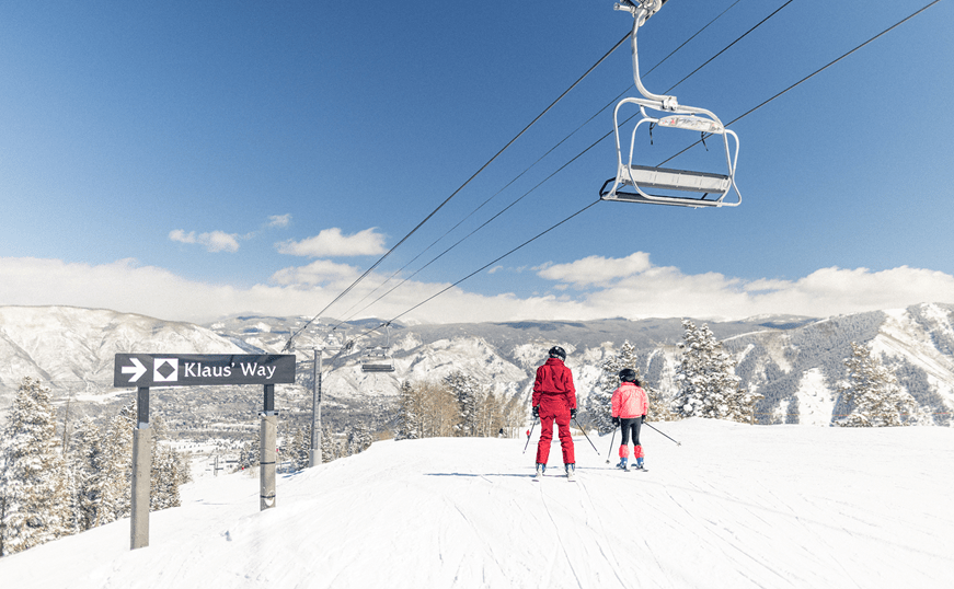 Buttermilk ski instructor and their student under a chairlift on a bluebird day on the slopes