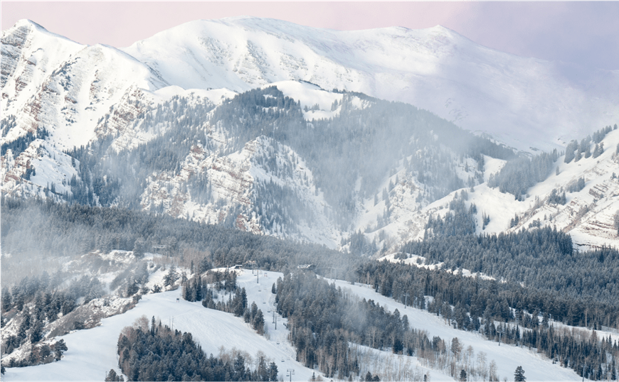 Scenic view of buttermilk mountain, clouds gather at the top of the hill with huge maroon bells peaks behind