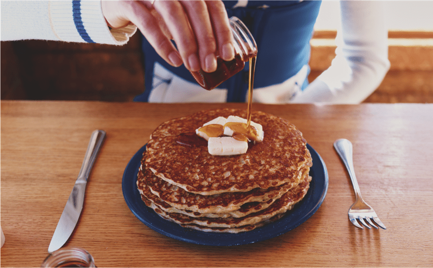 Woman pours syrup onto stack of perfectly cooked pancakes, at Bonnies in Aspen