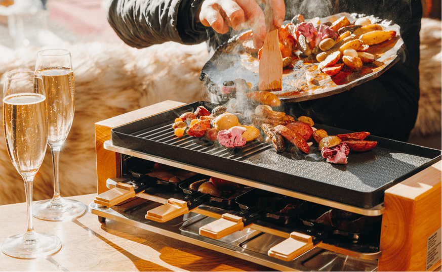 small table top grill, man sets mean in the hot top, with two glasses of champagne next to it at Cloud 9