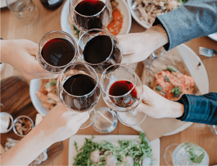 People cheers wine glasses over a table of food at aspen mountain on mountain dining