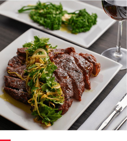 plate of steak with green salad on top