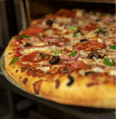 Close up of a toasted pizza crust, pepperoni's, olives and peppers grill on the top