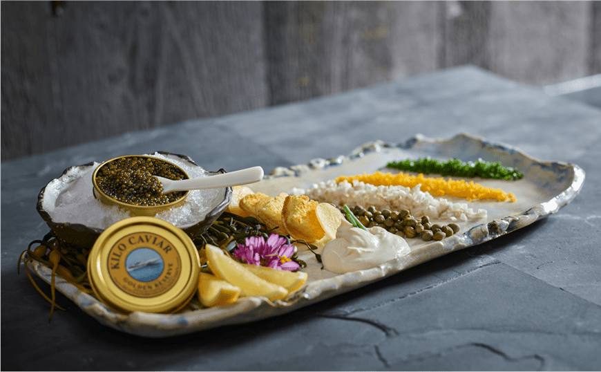 long plate on a slate table displays caviar, fruit and veggies, an app at Aspen Snowmass