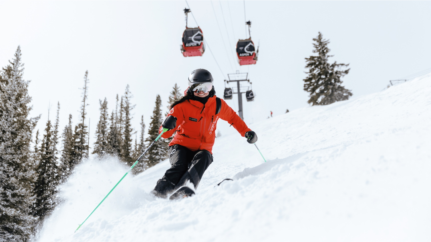 Ski Pro at Aspen Snowmass carves down a snowy hillside, under the aspen gondola