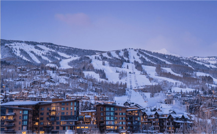 Winter view of Snowmass, dusk falls over the ski resort casting a blue glow to the town as lights twinkle in each window