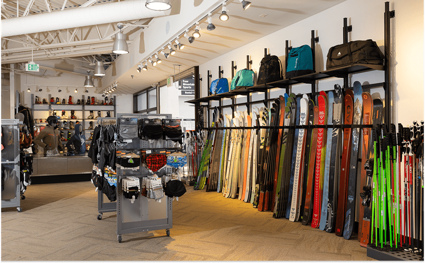 Interior view of four mountain sports, wall of new skies, boots for guests to try on, poles and a variety of ski and snowboard googles