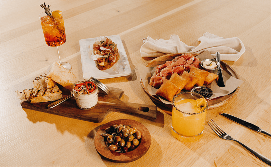 Wood table with array of food and drinks at Sam's, fine dining at snowmass