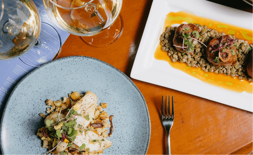 Table with a variety of food on the table, and two glasses of wine