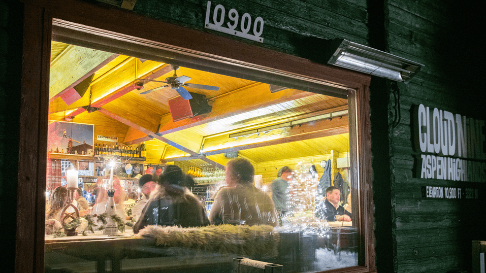 Window view of guests eating inside during a snowcat dinner.