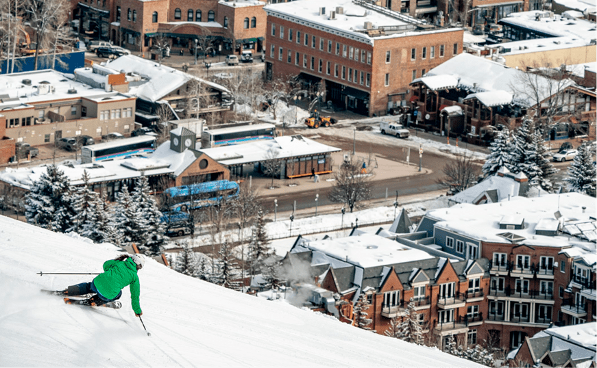skier carves down slopes overlooking the town of aspen