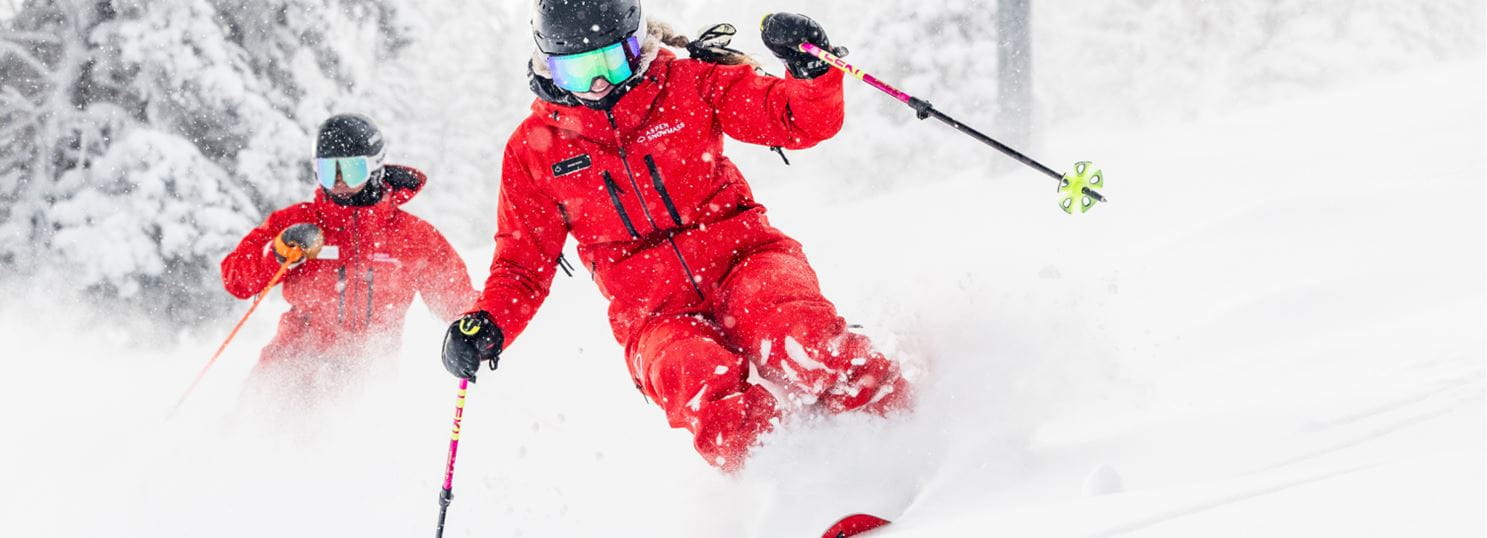Two ski pros in deep powder at aspen mountain