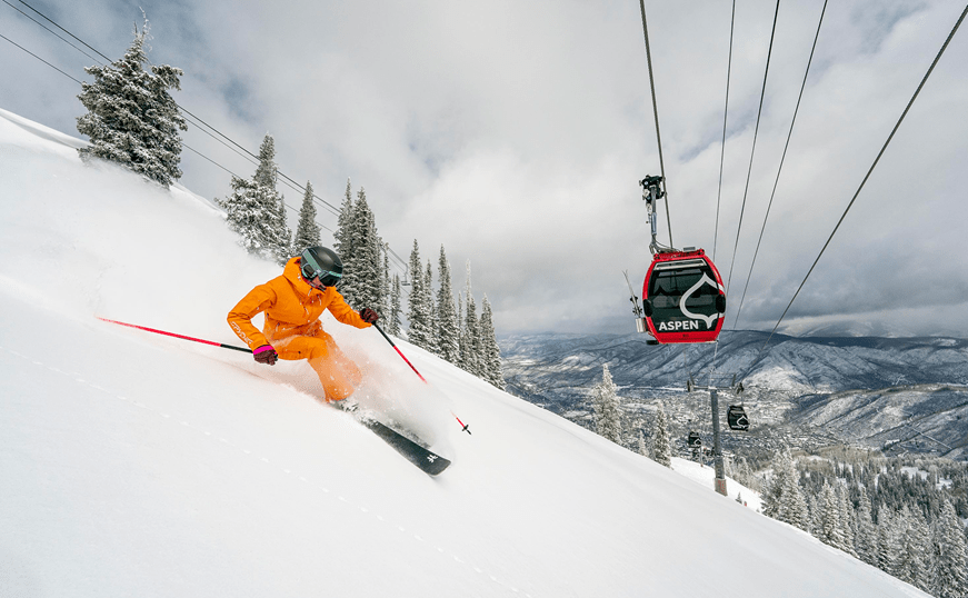 single skier under aspen gondola on snowy day