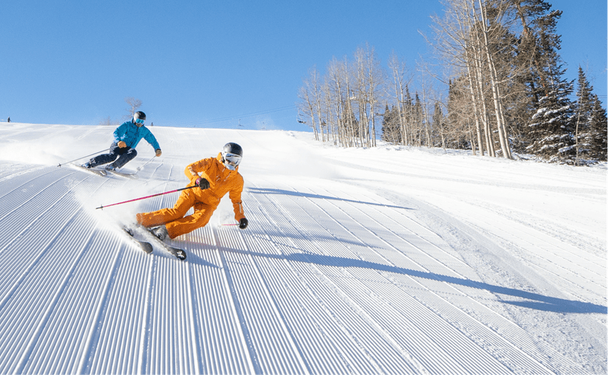 two people ski down groomed run at aspen mountain