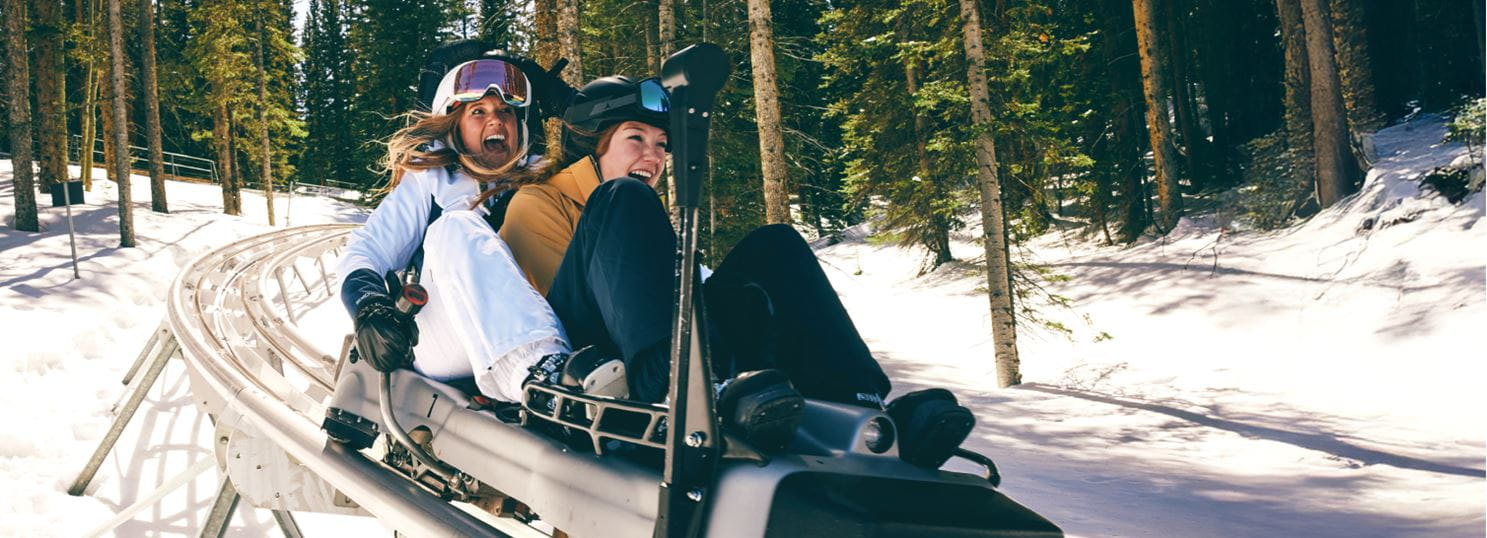 two women ride the alpine coaster in the winter