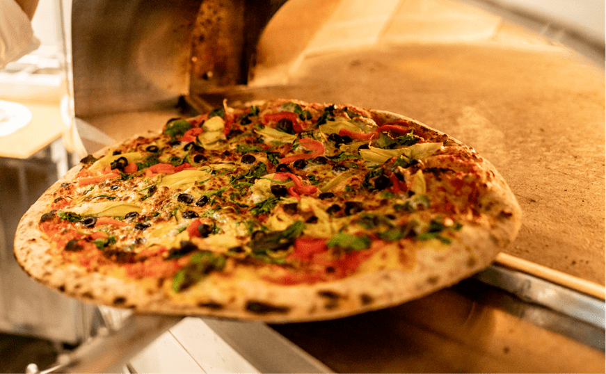 Pizza getting pulled out of pizza oven at Snowmass's elk camp