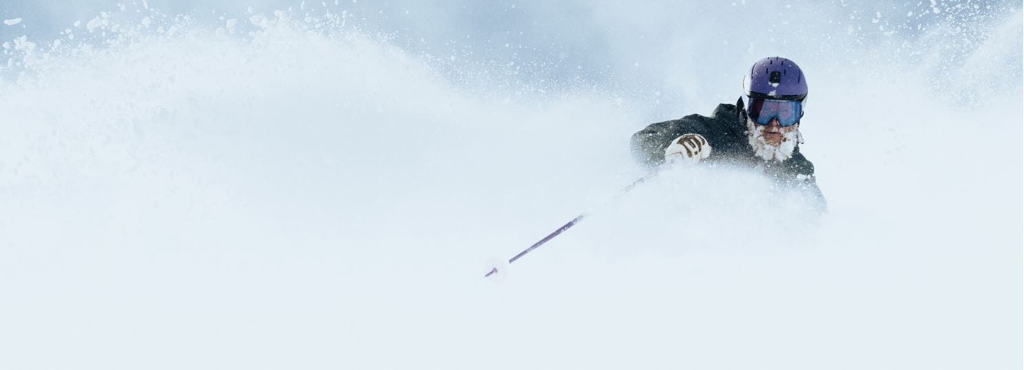 Skier with powder beard is nearly covered by deep snow