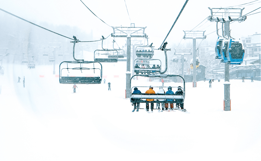 group of people ride on a ski lift on snowmass