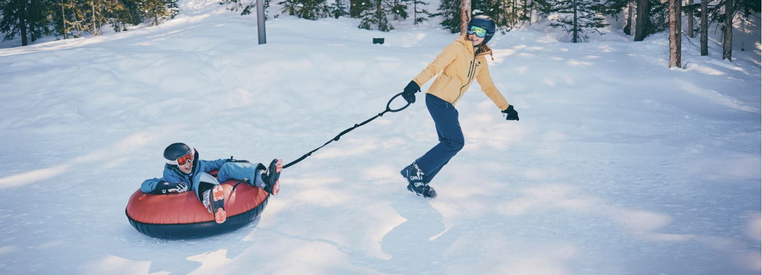 Woman pulls child in tube in snowmass tubing hill