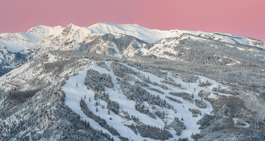 Areal, long shot of buttermilk mountain, covered in snow, with a beautiful, pink sky behind