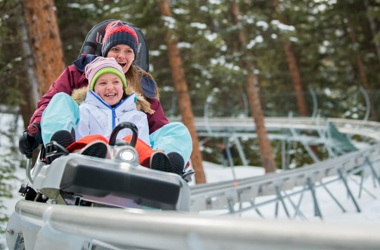 A mother and child ride down the Breathtaker alpine coaster at Snowmass