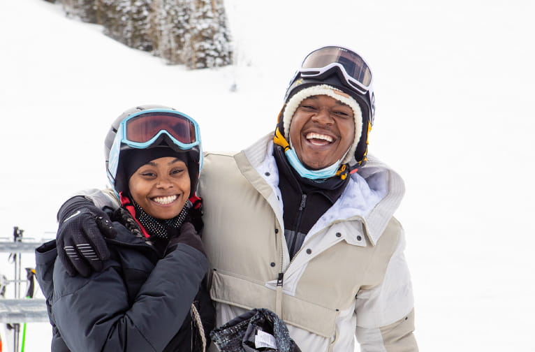 Two skiers share a life laugh and smile at the bottom of the slopes at Aspen Snowmass