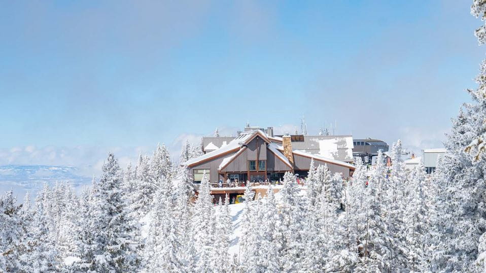 Sundeck from afar, surrounded by white snowy trees on a bluebird day