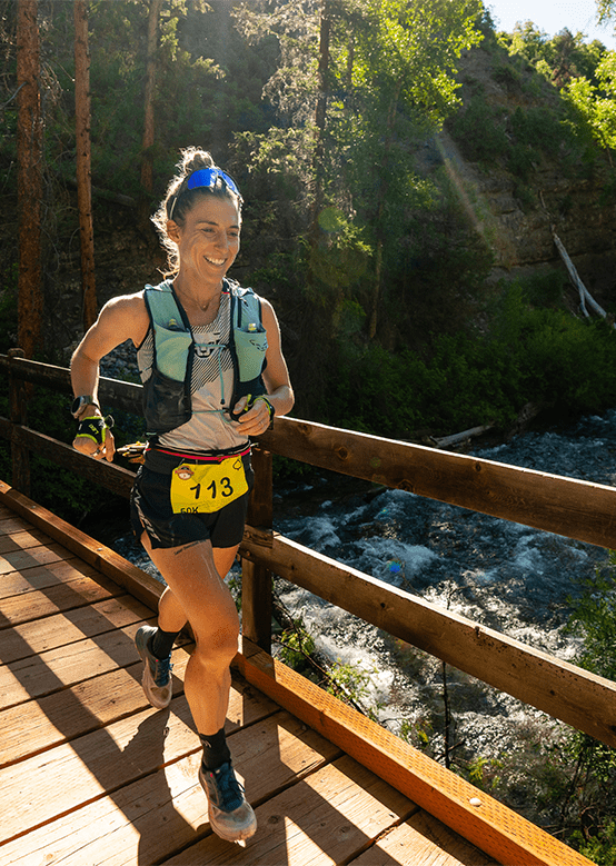 Woman runs over a bridge during the power of four running race at Aspen Snowmass