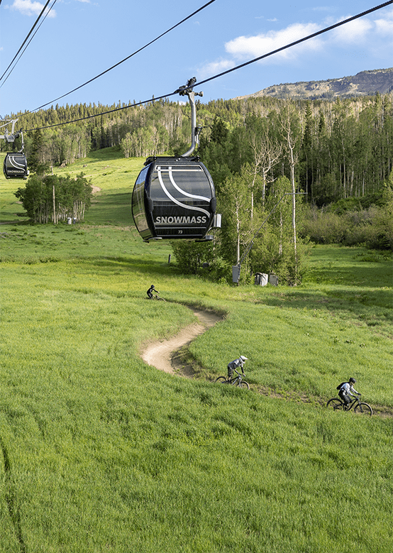 Bikers ride under the gondola at Snowmass Bike Park