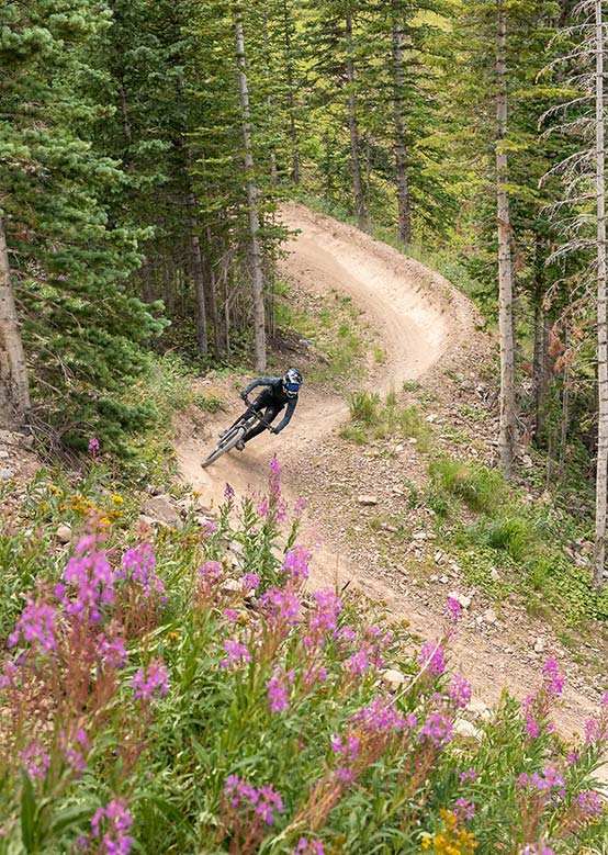 Mountain biker rider coming down an s-shaped trail at Snowmass Bike Park